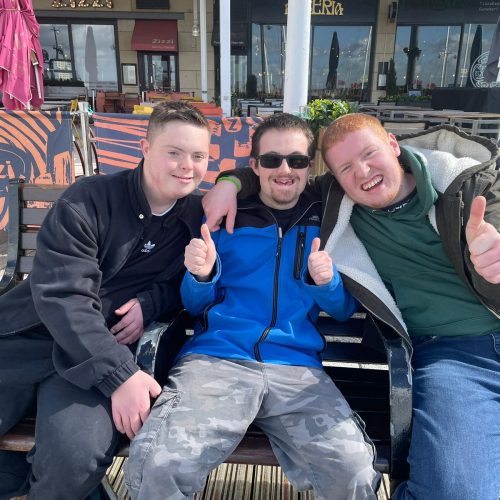 Three boys sat on bench posing for picture