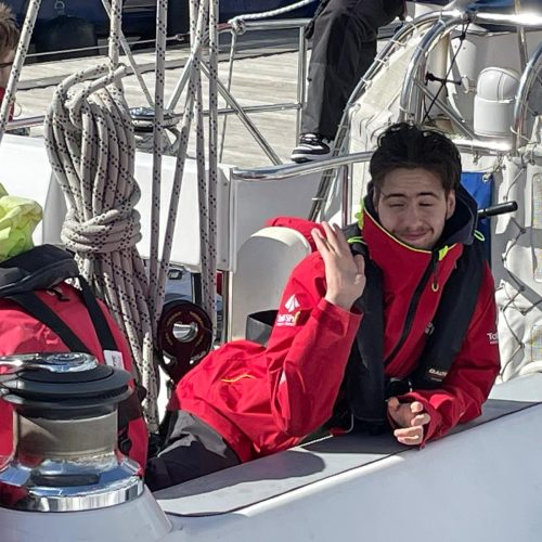 boy leaning on side of the boat waving