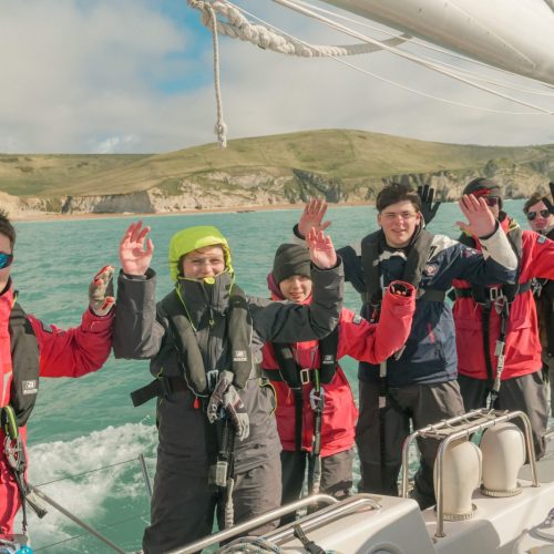 group photo holding hands up with Cowes, isle of wight in the background