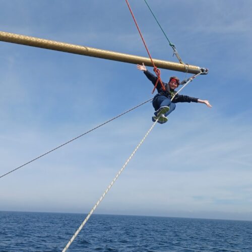 Young person climbing pole while sailing